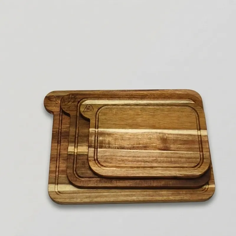 Three stacked acacia cutting boards with juice grooves in graduating sizes