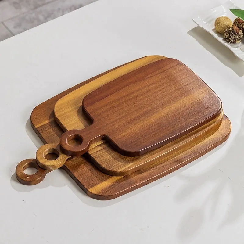 Three stacked wooden serving trays with ring-shaped handles on a table