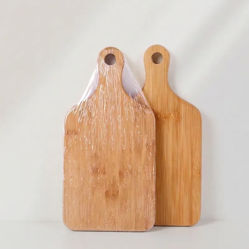 Shrink-wrapped bamboo cutting board with handle next to unwrapped board