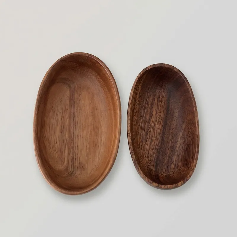 Two oval wooden boat trays displayed on a gray surface