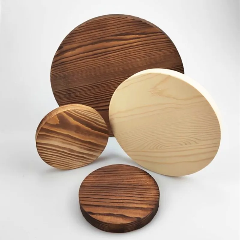 Four carbonized pine wood discs of varying sizes on white background