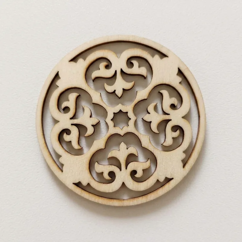 A circular wooden cutout displaying a hollow floral scrollwork pattern.