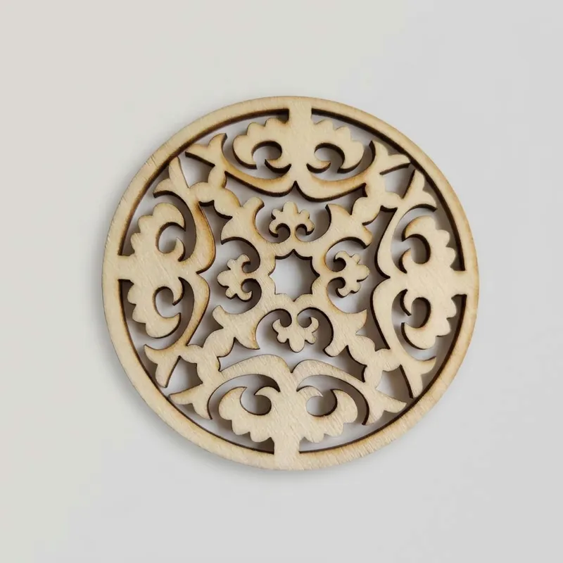 A detailed laser cut wooden disc with complex leaf and vine openwork.
