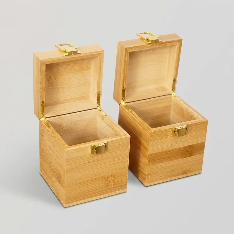 Two open square bamboo boxes with hinged lids and gold hardware on a gray background