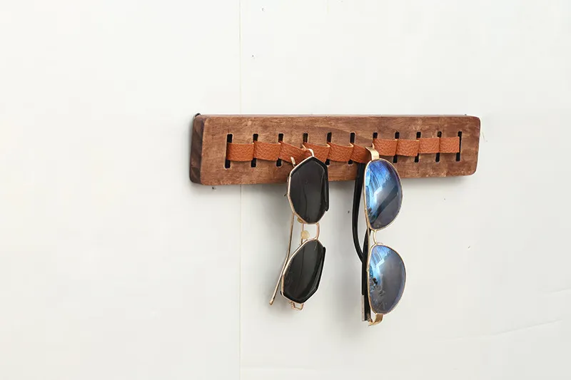 Wall-mounted wooden sunglasses rack displaying glasses against a light background
